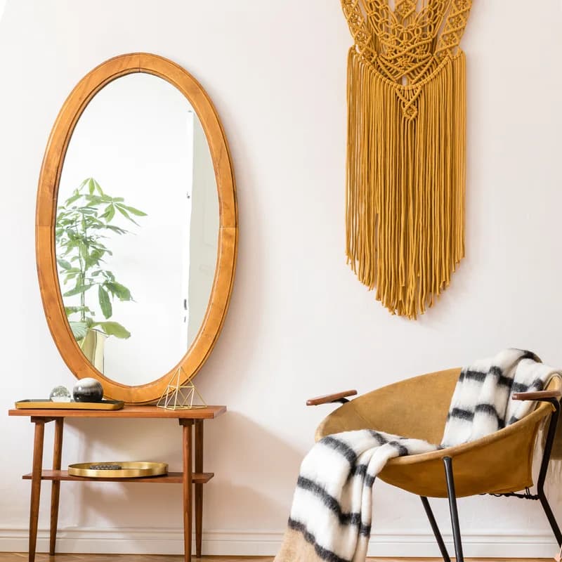 A mustard-colored chair, textured blanket, and round mirror in a quiet room